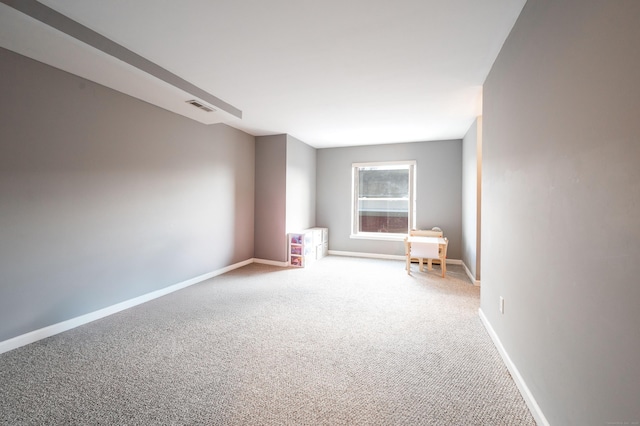 carpeted spare room featuring visible vents and baseboards