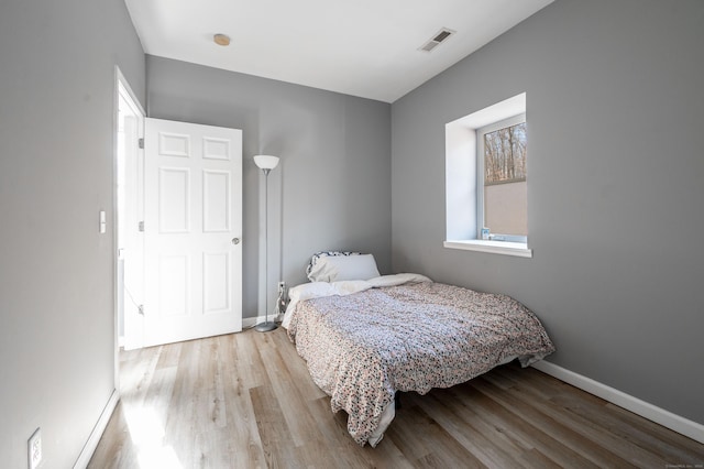 bedroom with visible vents, baseboards, and wood finished floors