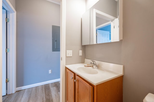 bathroom with baseboards, toilet, electric panel, wood finished floors, and vanity