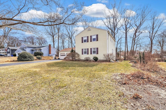 view of front facade featuring aphalt driveway, a garage, and a front yard