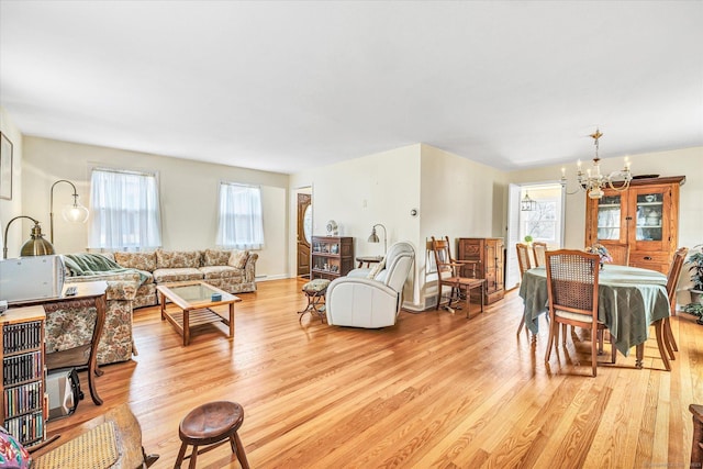 living area featuring a notable chandelier, plenty of natural light, and light wood-type flooring