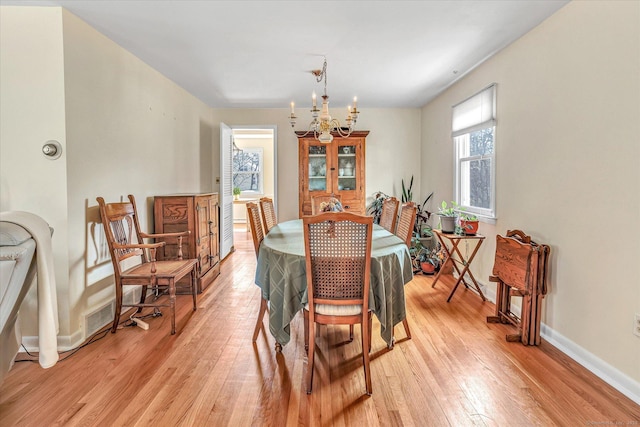 dining area featuring baseboards, an inviting chandelier, and light wood finished floors