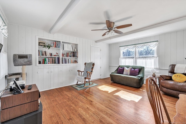 living area with beamed ceiling, wood finished floors, and ceiling fan