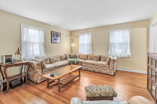 living area featuring a baseboard heating unit, light wood-style flooring, and a wealth of natural light