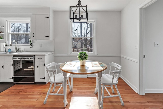 dining space with an inviting chandelier, light wood-style floors, baseboards, and a wealth of natural light