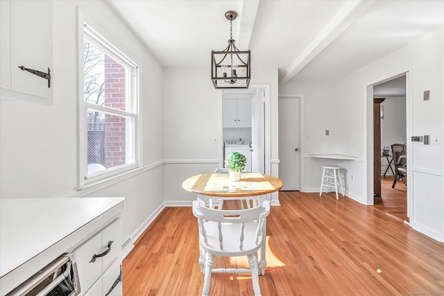 dining space featuring washer / dryer, a notable chandelier, light wood-style floors, and baseboards