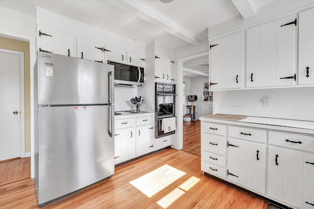 kitchen featuring beam ceiling, light countertops, appliances with stainless steel finishes, a warming drawer, and light wood-type flooring