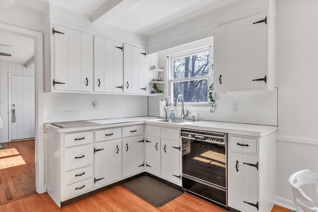 kitchen with a sink, dishwasher, light wood-style flooring, and light countertops