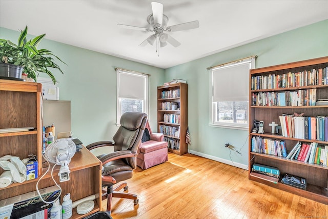 office featuring baseboards, wood-type flooring, a healthy amount of sunlight, and a ceiling fan