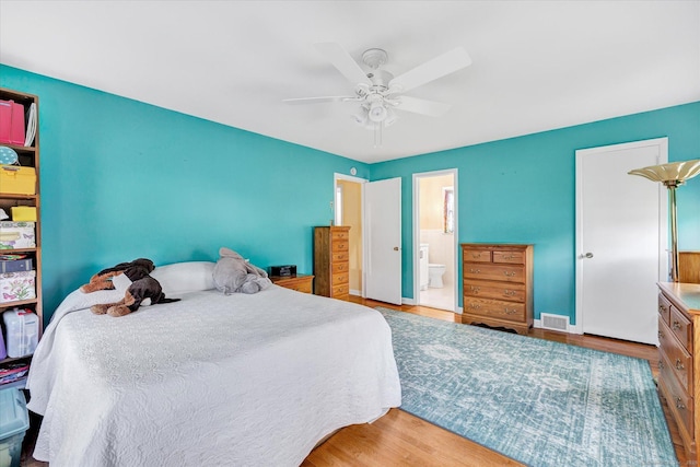 bedroom with ceiling fan, visible vents, wood finished floors, and ensuite bathroom