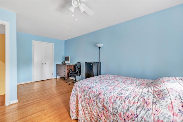 bedroom with a closet, baseboards, light wood-type flooring, and a ceiling fan