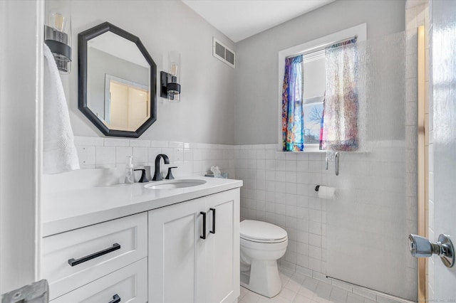 bathroom with vanity, visible vents, tile walls, toilet, and tile patterned floors