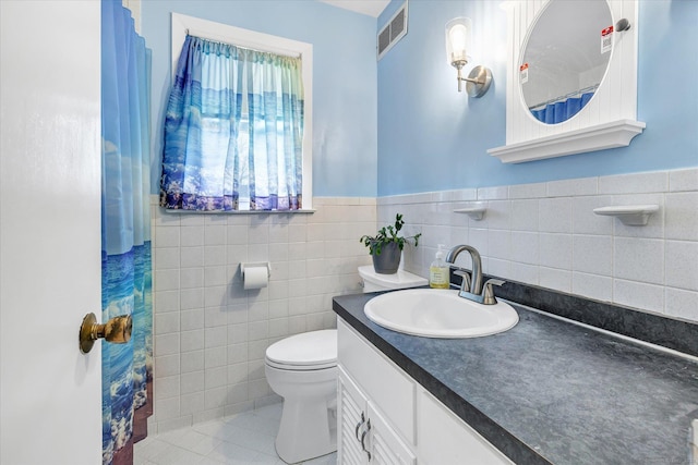 full bathroom with tile patterned flooring, visible vents, toilet, vanity, and tile walls