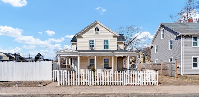 view of front of home with a fenced front yard, a porch, a shingled roof, and a gate