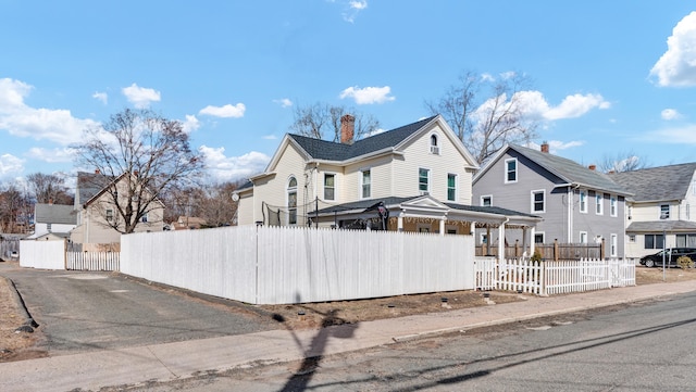 view of front of home with a fenced front yard, a residential view, and a chimney