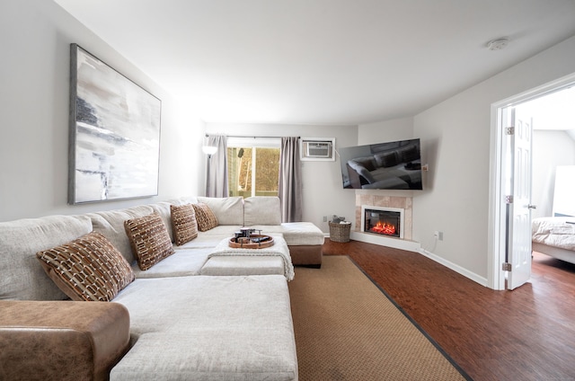 living area with a glass covered fireplace, baseboards, and wood finished floors