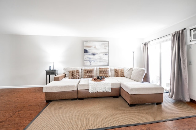 living area with a wall mounted air conditioner, baseboards, and wood finished floors