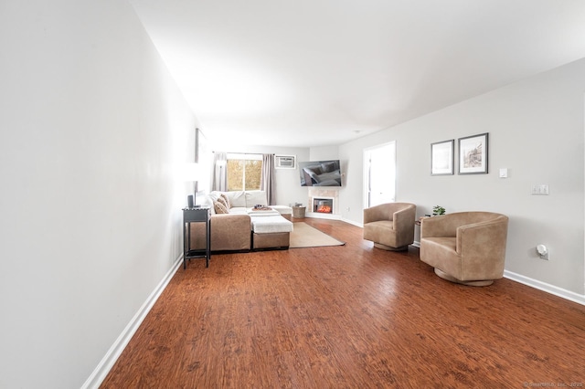 unfurnished living room featuring a glass covered fireplace, wood finished floors, and baseboards