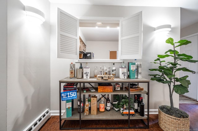 bar featuring a baseboard heating unit, a bar, wood finished floors, and baseboards