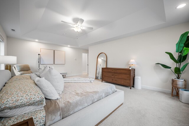 bedroom featuring visible vents, baseboards, a tray ceiling, recessed lighting, and light carpet