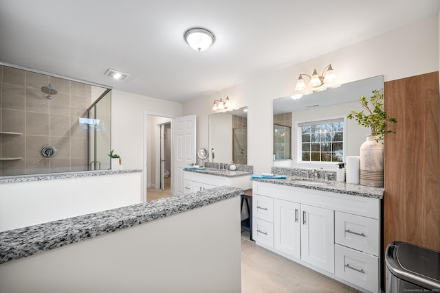 bathroom featuring a sink, visible vents, two vanities, and a shower stall