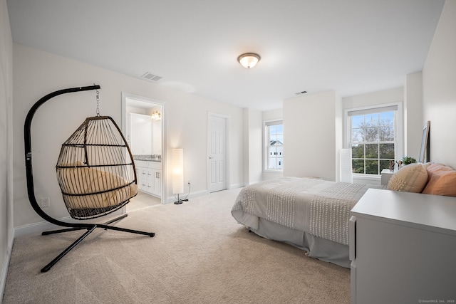 bedroom with connected bathroom, baseboards, visible vents, and light carpet