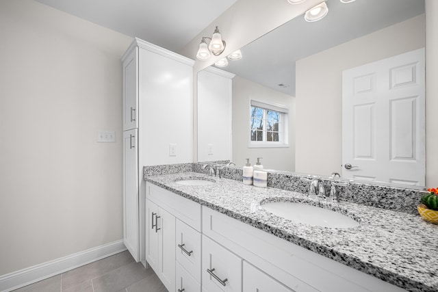 bathroom with double vanity, tile patterned floors, baseboards, and a sink