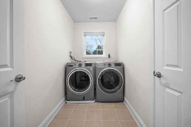 clothes washing area featuring washing machine and clothes dryer, visible vents, baseboards, light tile patterned floors, and laundry area