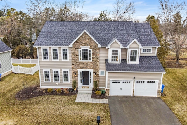 view of front of home featuring stone siding, fence, a front yard, and roof with shingles