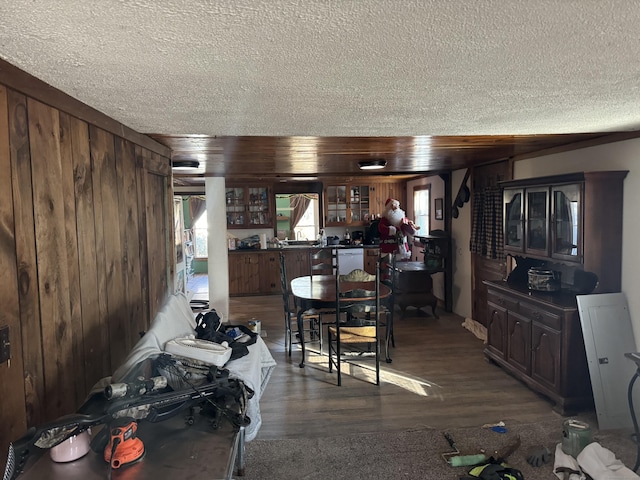 dining area with dark wood-type flooring, wood walls, and a textured ceiling