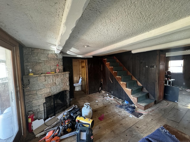 unfurnished living room with stairway, a textured ceiling, and a fireplace