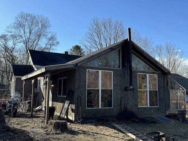 view of side of home featuring a chimney and roof with shingles