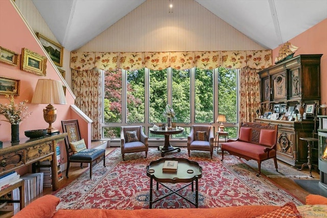 living area featuring wood finished floors, a baseboard radiator, and high vaulted ceiling