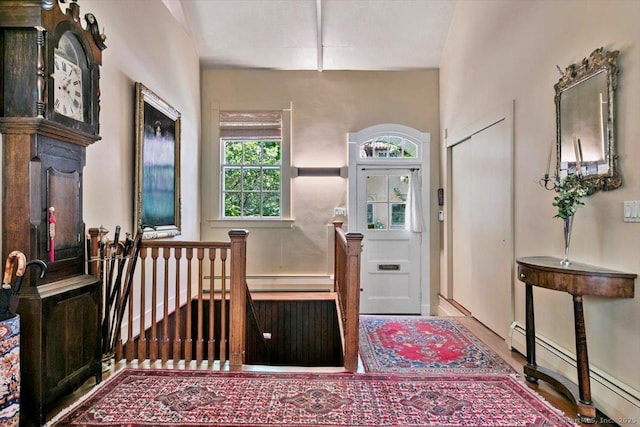 foyer entrance featuring wood finished floors and a baseboard radiator