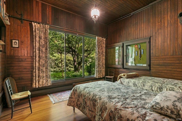 bedroom with wooden ceiling, wood finished floors, wood walls, and a baseboard radiator