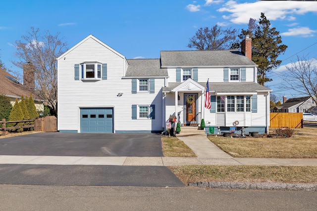 traditional-style home with an attached garage, a chimney, driveway, and fence