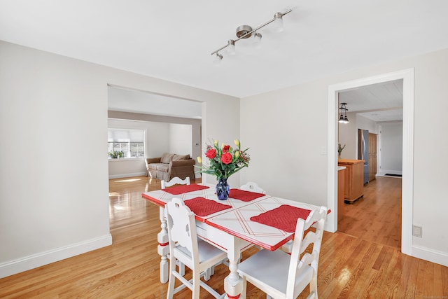 dining area with rail lighting, baseboards, and light wood-style floors