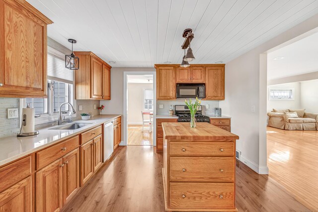 kitchen featuring light wood finished floors, a sink, appliances with stainless steel finishes, tasteful backsplash, and butcher block counters