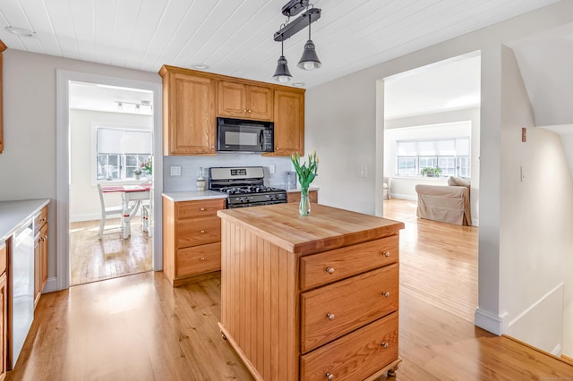 kitchen with butcher block countertops, decorative light fixtures, stainless steel appliances, light wood-style floors, and decorative backsplash