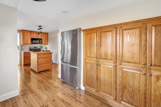 kitchen featuring brown cabinetry, baseboards, light wood finished floors, appliances with stainless steel finishes, and wooden ceiling