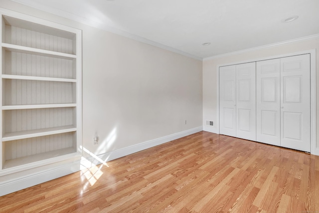 unfurnished bedroom with crown molding, wood finished floors, baseboards, and a closet