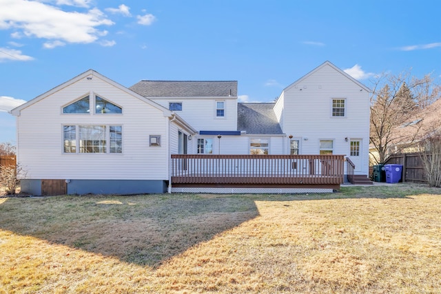 rear view of house featuring a lawn, fence, and a wooden deck