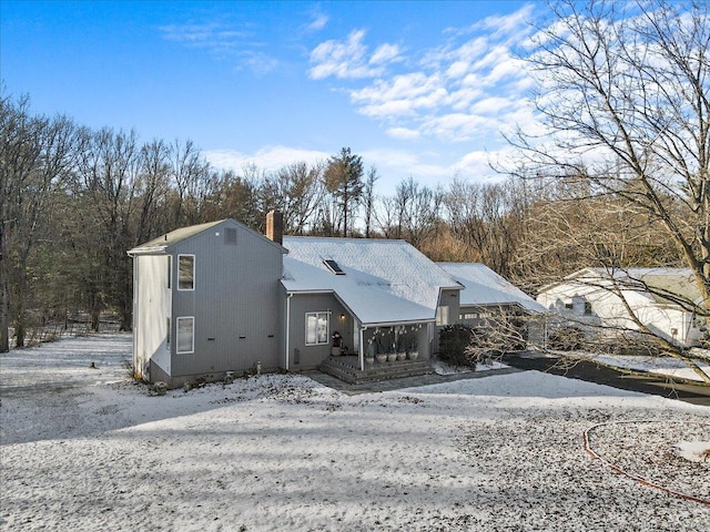 snow covered rear of property with a chimney