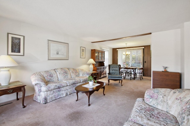 carpeted living area featuring visible vents, a textured ceiling, and an inviting chandelier