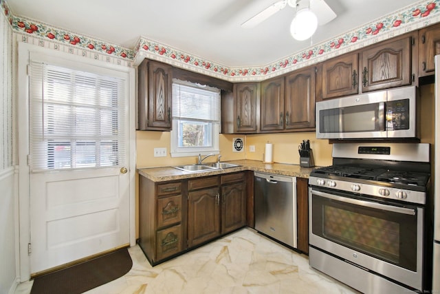 kitchen featuring a sink, ceiling fan, stainless steel appliances, dark brown cabinets, and marble finish floor