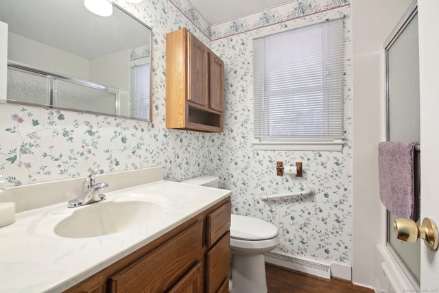 full bathroom featuring vanity, a baseboard radiator, wallpapered walls, a stall shower, and toilet