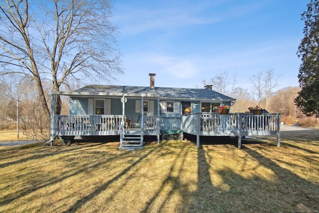 view of front facade with covered porch, a chimney, and a front yard