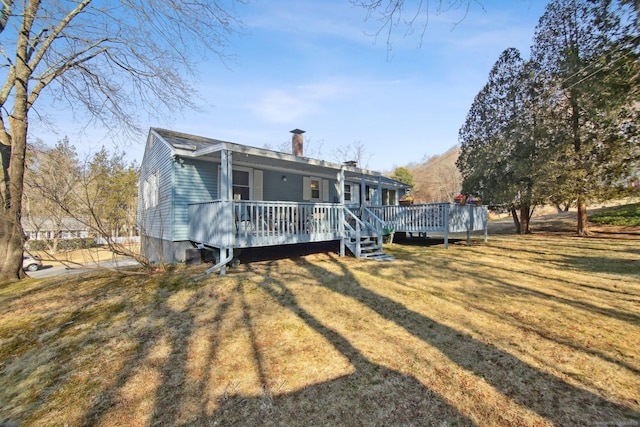 back of house with a yard, a wooden deck, and a chimney