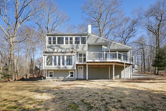 back of house featuring a chimney, a wooden deck, and a yard