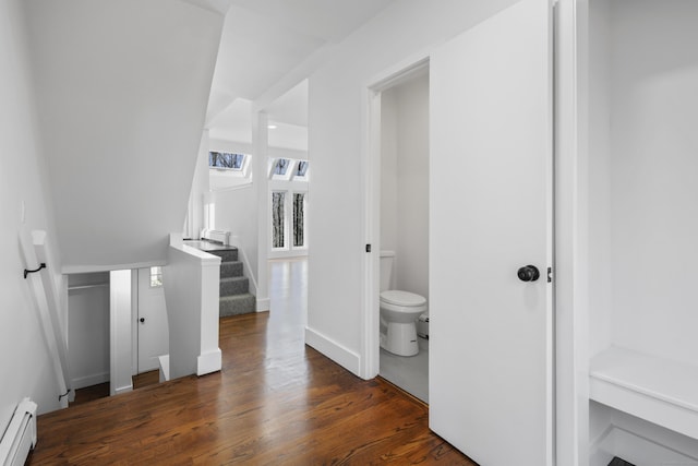 bathroom with a baseboard heating unit, baseboards, toilet, and wood finished floors